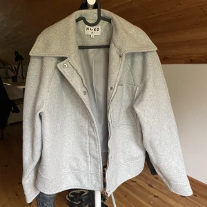 Na-kd kappa ljusgrå  - Kappa i strl 34 från NA-KD! Något noppig så därför lågt pris. Kommer göra en behandling innan den postas för att försöka få bort ”noppret” (pris kan diskuteras vid snabb affär!)