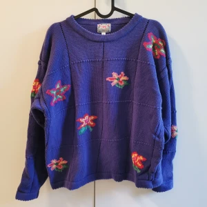 Lila blommig stickad tröja Tipo M - Lila stickad tröja med blommor från TIPO. Märkt storlek 14, tippar på medium? Inga blommor på ryggen (se bild 3), men ändå en riktig dröm! 🌸🌼🌻🌺