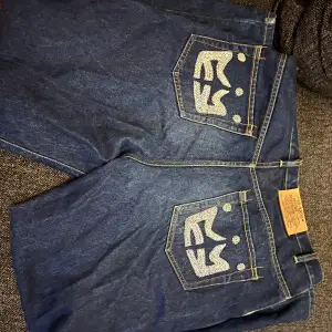 Väldigt snygga Y2K Jeans som har unikt tryck på båda bakfickorna, inga skador förutom ytterst lite slitna längst nere på byxorna. Storleken är 36 och är breda.
