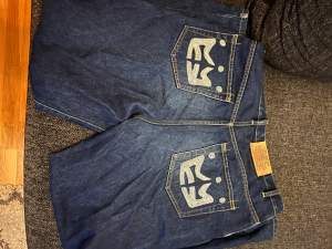Väldigt snygga Y2K Jeans som har unikt tryck på båda bakfickorna, inga skador förutom ytterst lite slitna längst nere på byxorna. Storleken är 36 och är breda.