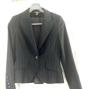 Kavaj - Fin, figursydd kavaj- jättebra skick, med 4 knappar längst ner på ärmen, grå/svart