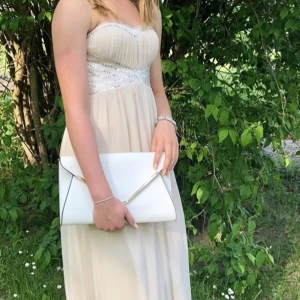 Balklänning  - Beige/rosa balklänning med paljettband. Klänningen är köpt i Hötorgshallen för ca 1500. En påse med extra paljetter tillkommer. Fint skick!