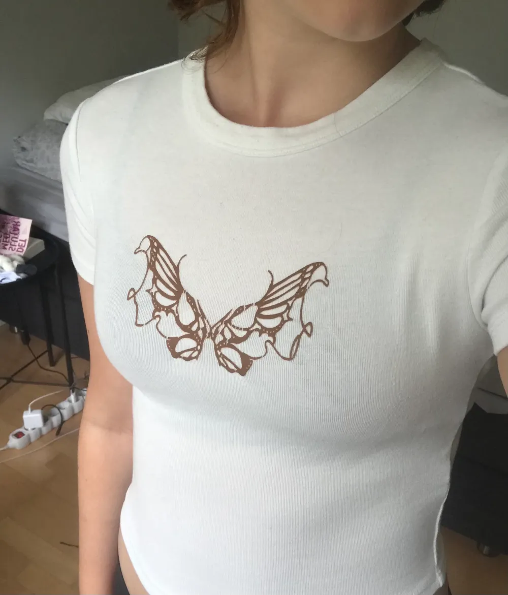 En jättefin vit croppad t-shirt med ett brunt fjärils tryck på. Säljer denna då den inte är min stil längre. Jättefint skick och har inte används många gånger.. Toppar.