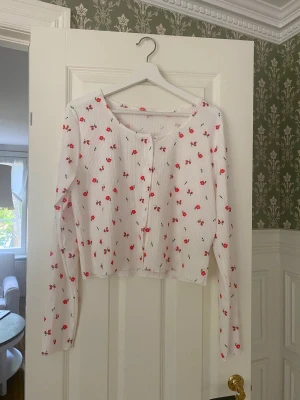 Söt vit topp med röda blommor  - Söt långärmad topp från shein, knappar fram i ribbat tyg! 🤍❤️sitter bra men inte supertajt på mig som är en medium/38 men det står XL på insidan. 