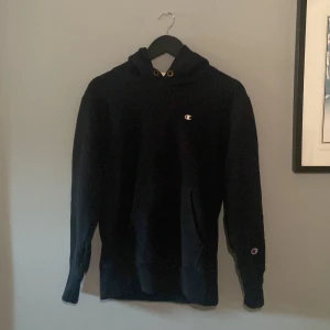 Champion Hoodie - Svart Champion hoodie med ett diskret broderat märke på bröstet. Nypris: 580kr