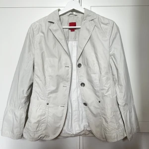 Tunn jacka - Inga defekter, i mycket gott skick. Färgen är i en ljus beige / grå färg. 