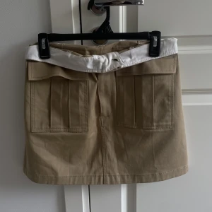 Beige kjol - Säljer denna coola kjol från Zara i storlek M. Den är jättefin att ha som den är. Men den har även en vit kant på insidan som man kan vika ut😊