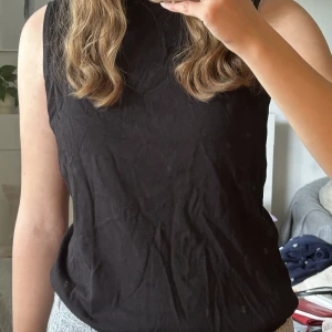 Västtopp - En svart finstickad västtopp. Den är storlek 42/44 men kan passa mindre storlekar beroende på hur man vill att den ska sitta. 