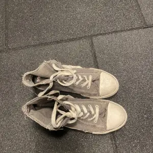 Gråa converse liknande skor. De är lite slitna men på ett coolt sätt:) 