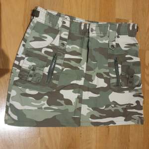 En kort militärfärgad kjol med små olika ditaljer 