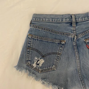 LEVIS SHORTS - LEVIS shorts köpta på second hand. Lite svårt att se storleken men tror det är W30 men passar mig med S och kan förmodligen passa någon som bär strl M. Fransar nertil och det är slitningar på båda bakfickorna ( kan skicka fler bilder på det). Second hand 