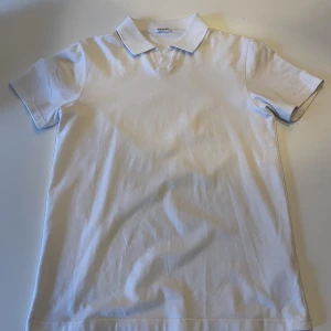 Piké - En vit pique från Filippa K, lite strechigt material. Tröjan har en liten svart fläck ungefär vid den högra armhålan. 