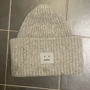 Acne mössa - Grå ”pansy n face” mössa från Acne Studios. Använd, men i fint skick! En liten tråd har gått upp därav litet litet ”hål”, men kan säkert enkelt sys ihop - se sista bild!