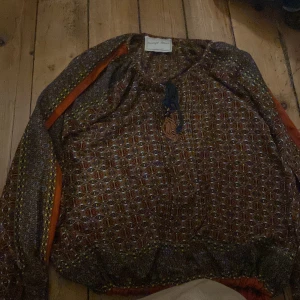 Mönstrad blus  - Söt blus från beautiful stories. Saknar en tofs på ena snöret men annars i väldigt bra skick 