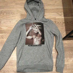 Grå Tupac Hoddie - Skit snygg Tupac hoddie, storlek Xs men passar även S. Har tyvär ingen användning för den längre så därav säljer jag vidare den, nyskick! Skriv för fler bilder☺️