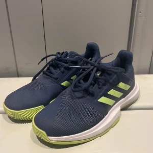 Adidas Court Jam XJ stl 36 1/2 (uk4) - Superhärlig bekväm men stabil Adidas tennissko stl 36 1/2 (UK 4) i marinblått och neongult. Nyskick och endast använd ett fåtal gånger. Nypris 500kr. 
