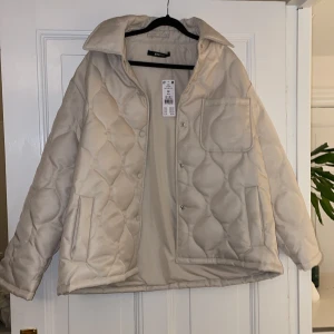Ny jacka från Gina  - Oanvänd vit/beige jacka från Gina som tyvärr inte kommit till användning. Storlek 38. Inköpt för 699kr, frakt tillkommer