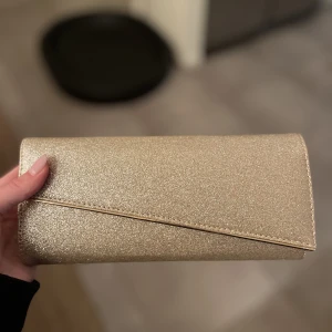 kuvertväska i guld - jättefin kuvertväska i guld. kedjan går att stoppa in i väskan. använd vid ett tillfälle😍