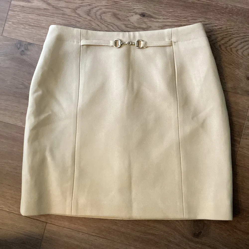 Kort beige kjol med gulddetals fram från H&M!🎀Har använd ett par gånger endast och har jättebra skick💕. Kjolar.