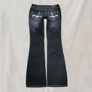 Jeans - Midja:77 innerben:82 Jeans med detaljerade bakfickor. Storlek 7, vet ej vad det motsvarar men uppskattar att de sitter som en S. Endast en sten saknas enligt sista bild. Endast pyttesmått nötta vid ex ficka och fotändar men överlag mycket fina i skicket!🤍