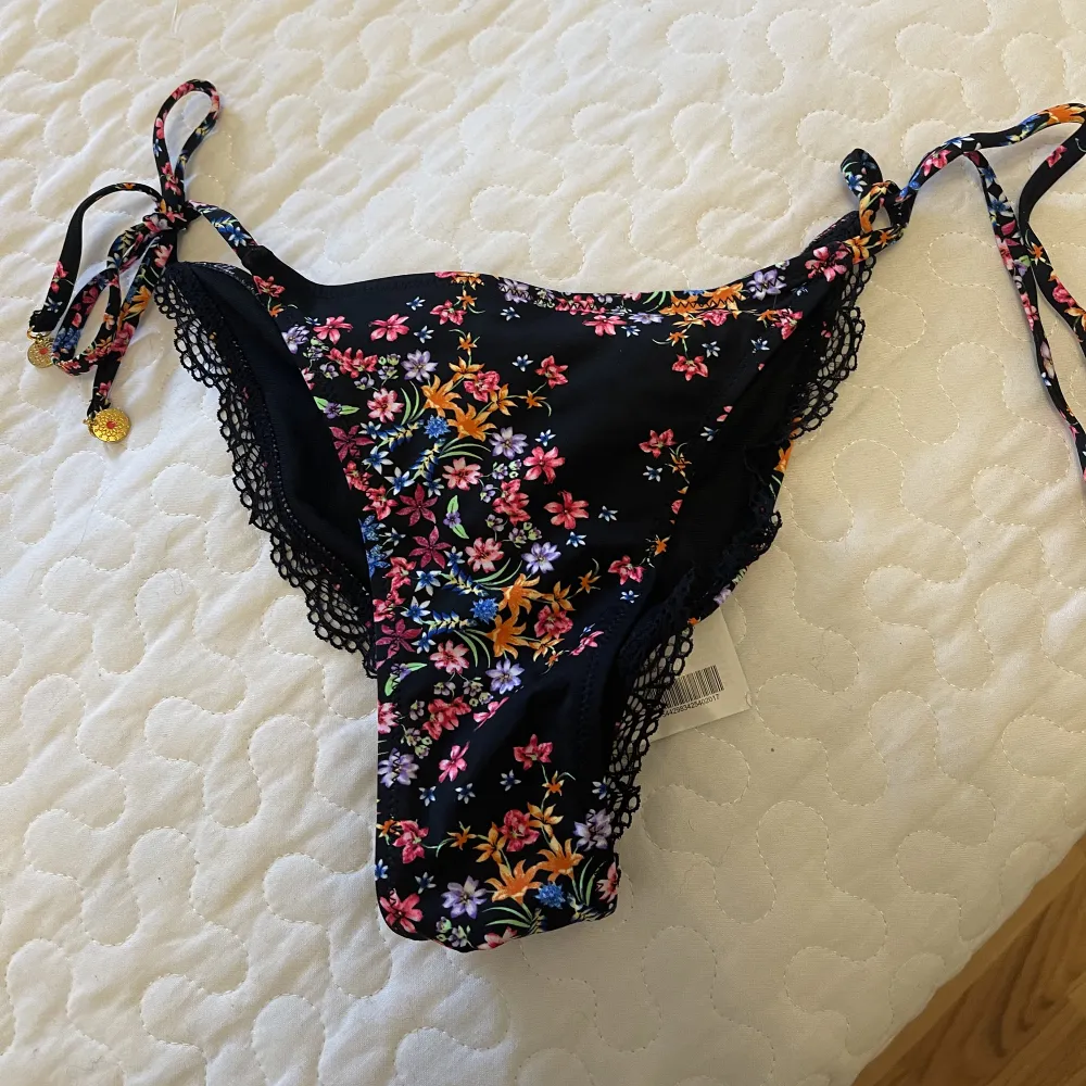 Helt nya svart Bikinitrosa med färgglada blommor. Storlek XS knyt i sidorna . Shorts.
