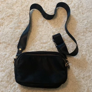 Svart väska - Super snygg väska med guld detaljer. Den är även smidig och Sthlm-stil. Den har två fack då man får plats med ganska mycket 
