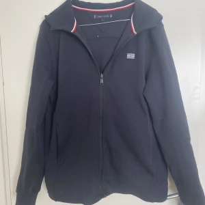 Tommy hilfiger Zip Hoodie - En Zip Hoodie från Tommy hilfiger i STRL M köpt på Urban Modern i Helsingborg.  Storlek: M Condition: 8/10 - lite sliten vid höger arm samt vid dragkedjan.  Nypris: 1600 :-  Köparen står för frakt!