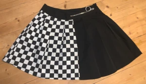 Kort halv rutig/schack mönster halv svart kjol - Köpte den 2021 men har sen dess växt ur den. Den passar till XS/Small och kanske Medium om man är envis. Den är rätt så kort, rekommenderar att ha shorts under. Inte använd så ofta. 