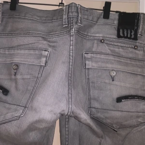 Lågmidjade gråa jeans✈️ - Snygga gråa jeans med stora bakfickor med coola detaljer. G- Raw från Urban🥰Har inga bilder på osäker på storlek då det är från herr avdelningen. Ca W31 L33