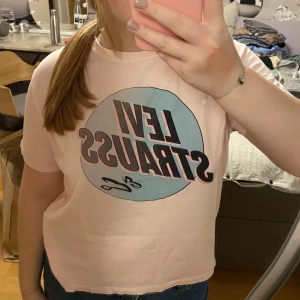 En Levi strauss t-shirt  - En fin rosa blå Levi Strauss t-shirt i strl XS. Har ett litet litet hål långt ner på tröjan men det syns bara på nära håll 