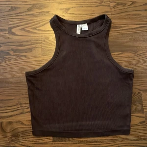 Mörkbrun tanktop - Mörkbrun tanktop från H&M, bra skick och knappt använd.