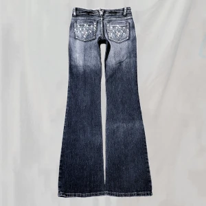 Jeans - Midja:70 innerben81 Jeans med rhinestones. Sitter midwaist, rakt/lite bootcut. Håller upp på bild. Endast enstaka stenar saknas(tvättas varsamt för hållbarhet).Knapp kan kännas lite lös men gjord så. Eventuellt smått nötta men överlag mycket bra skick!🤍