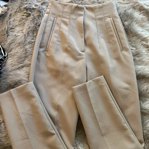 Mörkbeiga kostymbyxor från zara - Ett par högmidjade kostymbyxor köpt från zara. I storlek XS. Säljer för att dom är små på mig. Fortfarande i gott skick.
