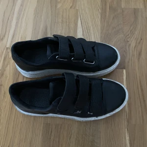 Svarta sneakers - Svarta sneakers med kardborreband. Säljes pga använder inte längre. Jättesnygga och sköna!! 