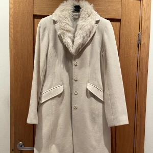 Fodrad kappa - Jättefin fodrad kappa, pälsen är avtagbar och den är lika fin med och utan. Kappan är gjord i 80% ylle och är tillverkad i Italien. 