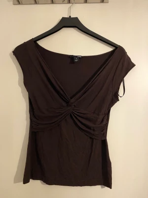 T-shirt med korsning fram - Fin t shirt i tunnt material med korsnings detalj framtill, är använd men i bra skick. 