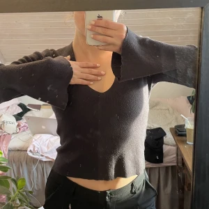 Stickad tröja - Jättesnygg stickad tröja som jag inte använder längre. Utsvängda ärmar, v-ringad, mörkgrå färg. Som referens för längden har jag lågmidjade byxor på mig till.