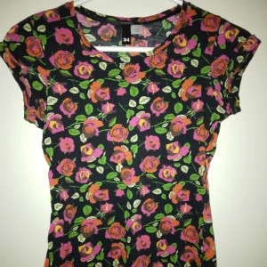 Svart blommig kortärmad topp med röda rosor. Strlk: 34, / XS. Mjuk bomull. Felfri. - Svart blommig kortärmad topp med röda rosor. Strlk: 34, / XS. Mjuk bomull. Felfri.