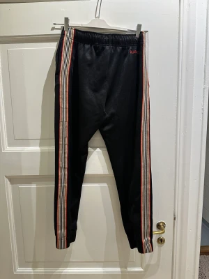 Burberry Mjukisbyxor - Slimmade mjukisbyxor från Burberry storlek S. Ganska använda, noppriga framsida. Men dom är svarta så det syns inte så mycket. Helsvarta med stripes på sidorna 