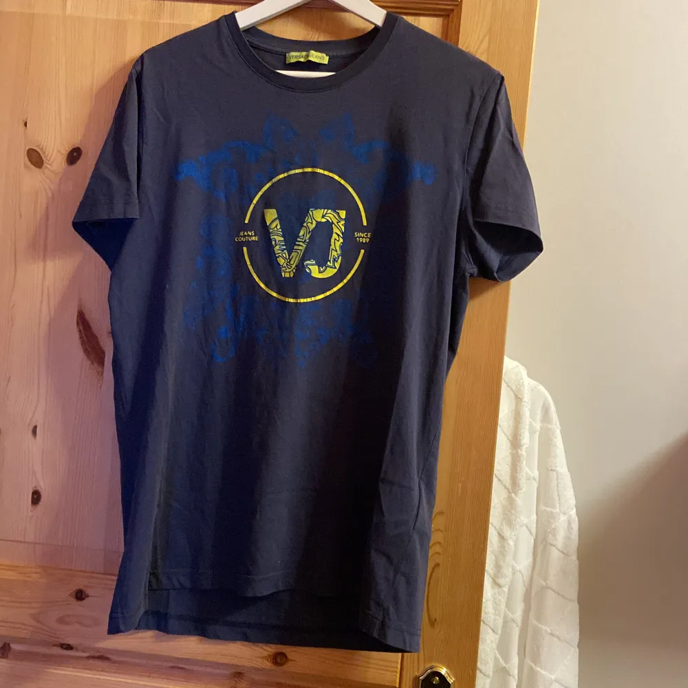 Versace T-shirt, storlek M. Ända problemet med den är missgärning från de blåa som färgat av sig på det gula, även lite sprickor i själva texten i märket i mitten.. T-shirts.