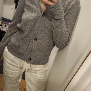 Stickad kofta - Stickad kofta med knappar och fickor. Superfin att ha både som tröja och att slänga över en topp! Köpt för 500 kr. Använd ca 3 gånger då det tyvärr inte var min stil