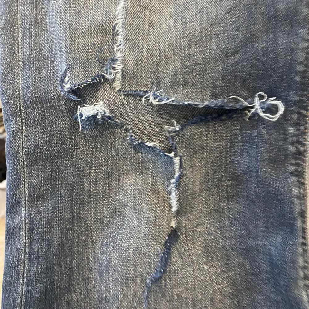 Lågmidjade Lee jeans med bootcut, hål på ena benet. Storlek W28 L33 passar S. Jeans & Byxor.