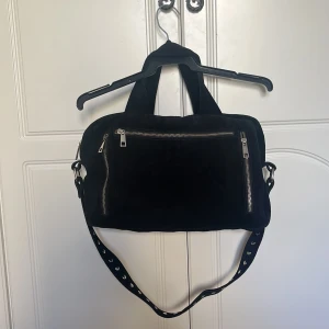 Väska Núnoo - Stor svart väska från Núnoo i mocka med silverdetaljer. Rymlig med många fack i gott skick. 
