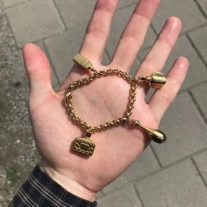 Armband i guldfärg - Fint armband med massiva hängen. Köpte på loppis för ett tag sedan för 250kr men inte kommit till användning.   Okänt märke och metall, men väger en del pga hängena