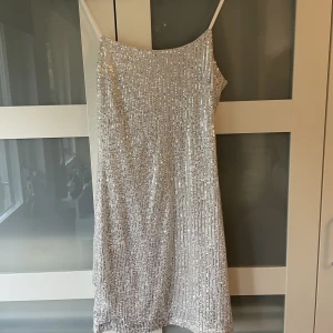 Silvrig paljettklänning - Säljer min fina silvriga paljettklänning från Missguided!! Använd 1 gång på en temafest. Sååå snygg.  Justerbara band och dragkedja i ryggen.  3 FÖR 2 på min sida!!