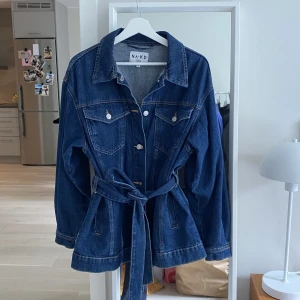 Jeansjacka - En mörkblå jeansjacka från NAKD i storlek 36. Oversized och med löstagbart skärp! 