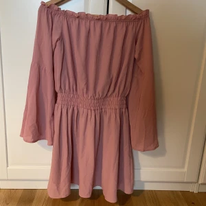 Off shoulder klänning - Supersöt miniklänning med off shoulders i rosa. På insidan finns en liten gummiremsa så att klänningen  sitter kvar mot huden. Aldrig använt den, säljer för att det inte riktigt är min stil