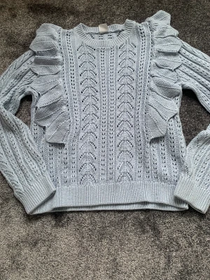 Blå stickad tröja med volang  - En stickad fin blå tröja med volanger. 