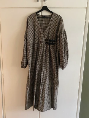 Oversized byxdress i gingham  - Super luftig och oversized byxdress i Gingham. Något croppad i ben och armar med dekorativa spännen och omlottdesign på överdelen. Aldrig använd, hann dock tycka loss taggarna! Super fin och tunn. Ge den, den kärleken som jag aldrig hann 💔🥲