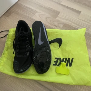 Spikskor  - Spikskor från Nike som endast är använda en gång. Kommer med verktyg för skruvar + bag till skorna. Storlek 40 men passar mig som har strlk 38. De är svarta med lila/blå detaljer. 